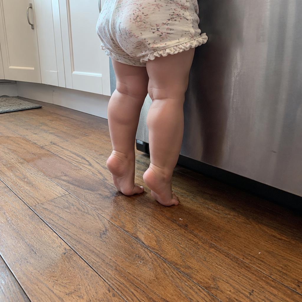 Toddler's bare feet standing tiptoe on a wood floor